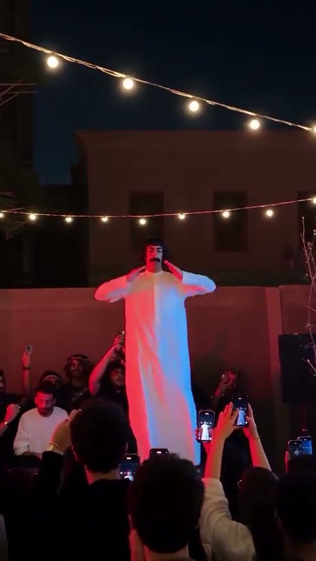 Performer Channels Borat Persona for Crowd at Nighttime Event