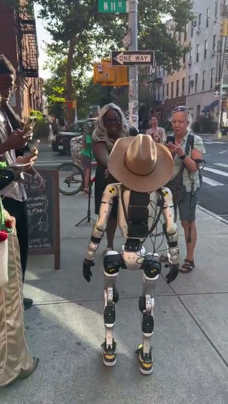Woman Confronts Cowboy-Hatted Robot on City Sidewalk