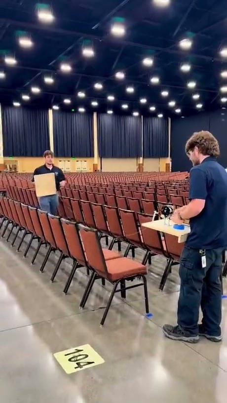 Precision Setup: Workers Use a Jig to Perfectly Align Rows of Chairs
